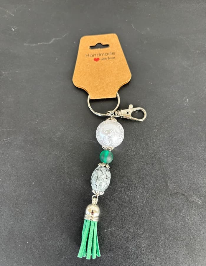 White swirl bead charm with a green tassel